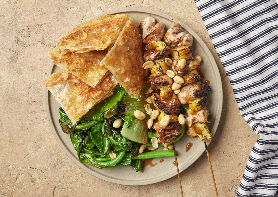 Rojak chicken and pineapple skewers with roti, Asian greens and roasted peanuts