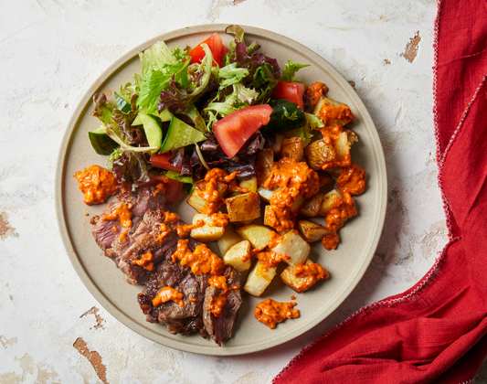 Beef & Romesco Sauce with Crispy Potatoes, Mixed Lettuce, Cucumber & Tomato Salad