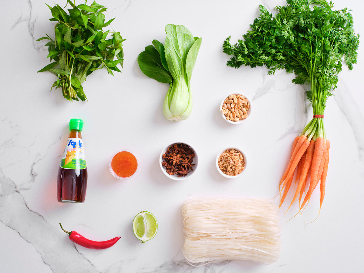 South East Asia Meal Kit ingredients laid out: herbs, bok choy, carrots, chilli, sauces and noodles