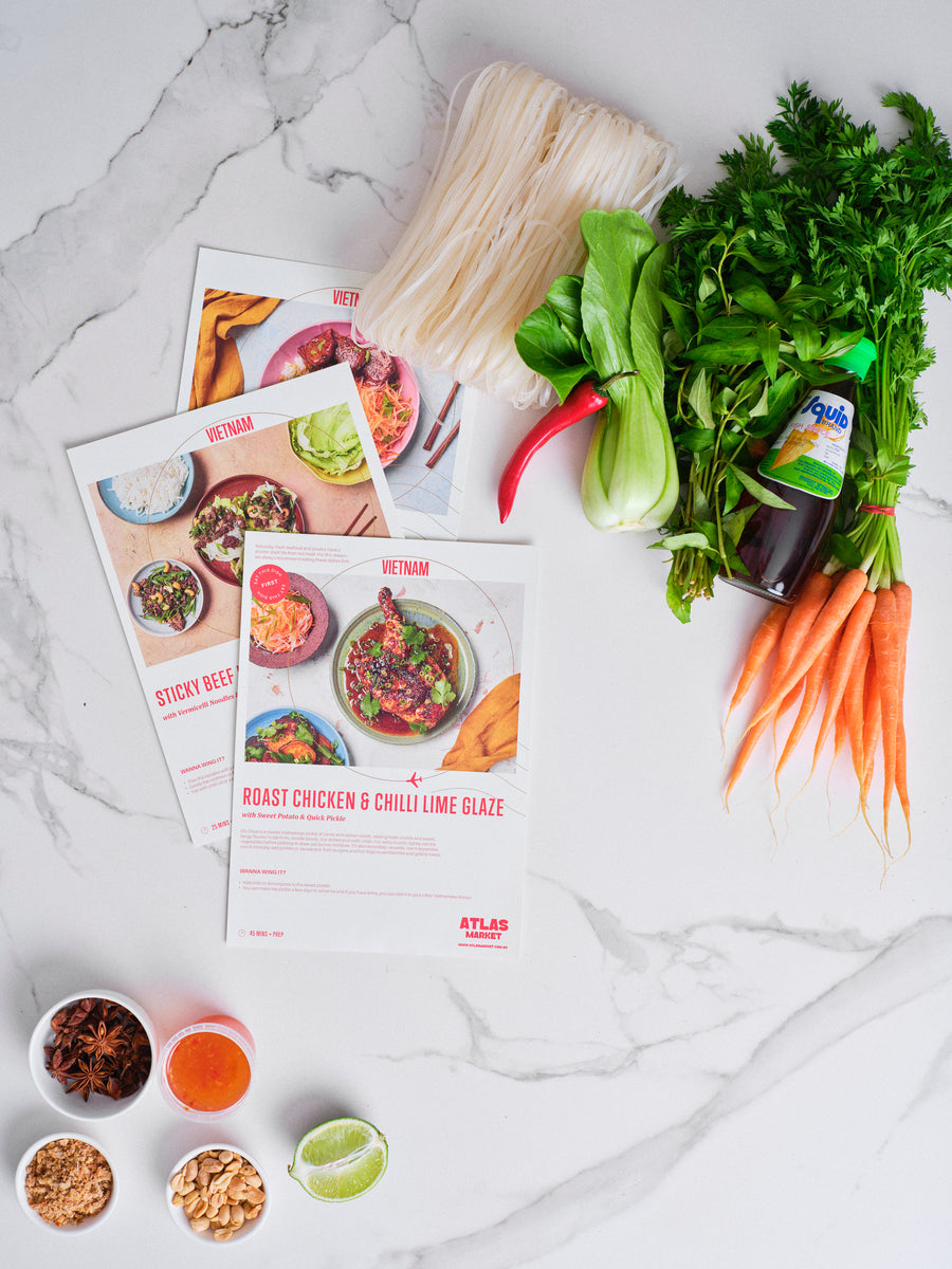 Fresh produce, sauces and recipe cards laid out on marble