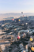 Hot air balloons floating over a landscape with rocky terrain