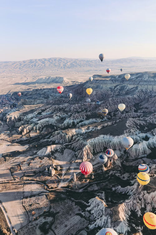 Hot air balloons floating over a landscape with rocky terrain
